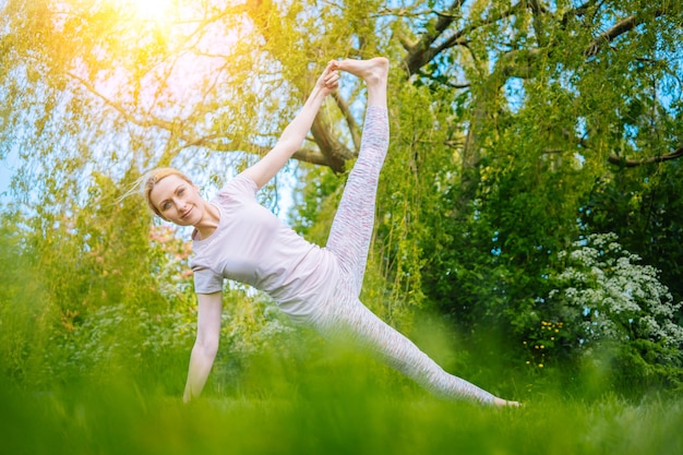 Giovane donna che fa yoga asana nel parco ragazza che allunga esercizio in posizione yoga felice donna in buona salute