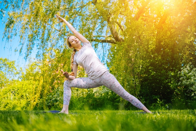 Giovane donna che fa yoga asana nel parco ragazza che allunga esercizio in posizione yoga felice donna in buona salute