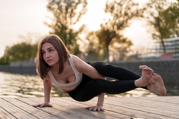 giovane donna che fa yoga in riva al lago