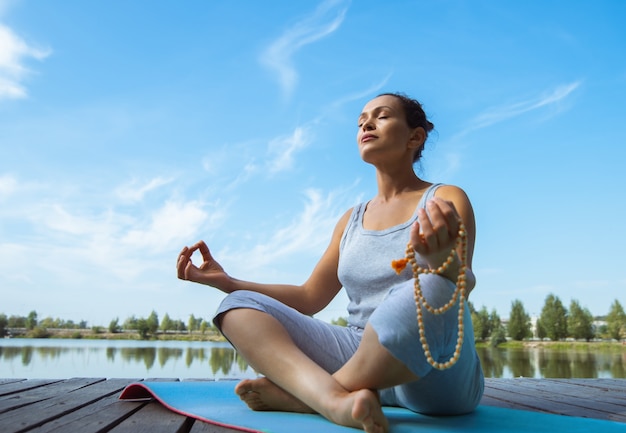 giovane donna che fa yoga in riva al lago