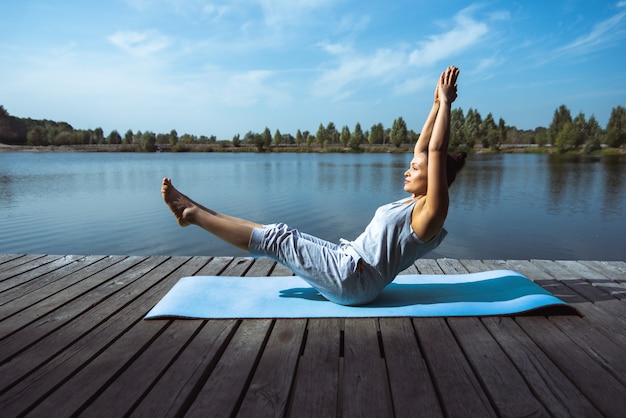 giovane donna che fa yoga in riva al lago