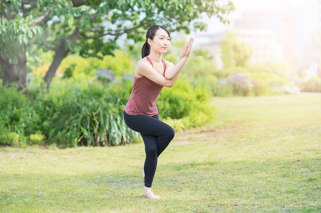 Giovane donna che fa yoga in un parco verde in bella giornata