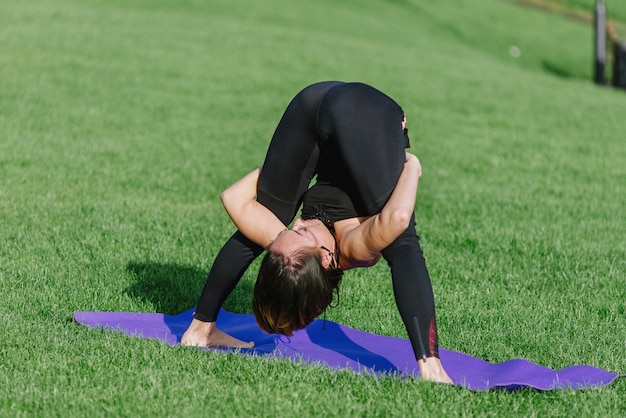 Giovane donna che fa yoga nel parco la mattina in autunno.