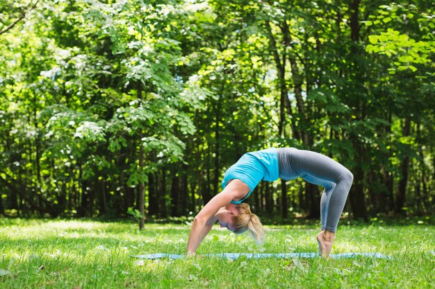 Giovane donna che fa yoga nel parco