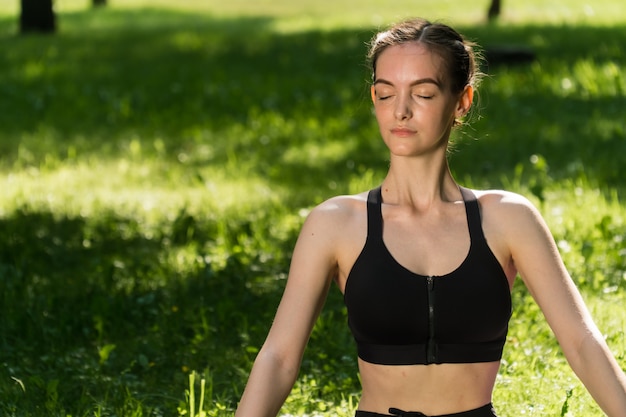 Giovane donna che fa yoga nel parco