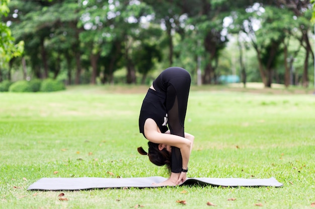 Giovane donna che fa yoga nel parco