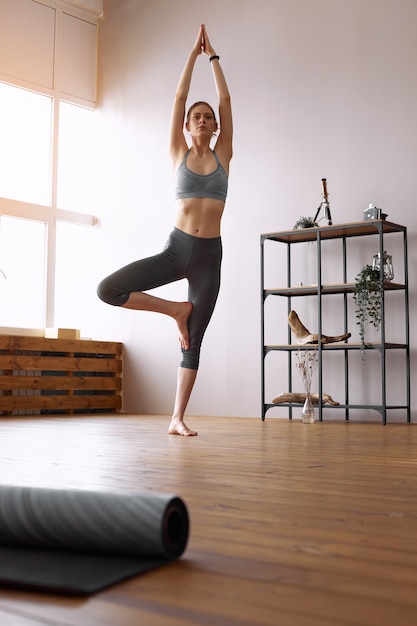 Giovane donna che fa yoga posa dell'albero, Vrikshasana