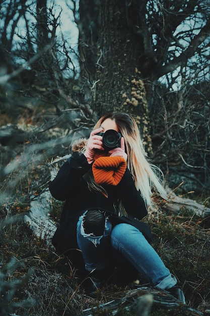 Giovane donna che fotografa con la macchina fotografica all'aperto