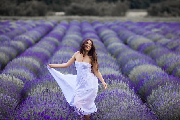 Giovane donna che funziona nel campo di lavanda. Bella donna su sfondo floreale estivo