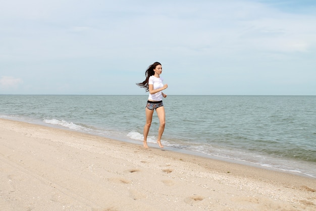 Giovane donna che funziona sulla spiaggia