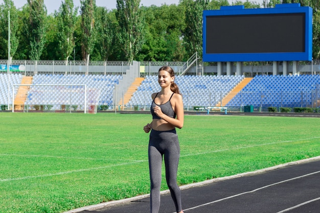 Giovane donna che funziona sullo stadio della pista.