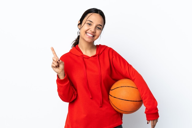 Giovane donna che gioca a basket isolato mostrando e alzando un dito in segno del meglio