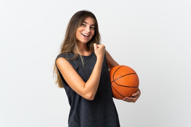 Giovane donna che gioca a basket isolato su sfondo bianco che celebra una vittoria