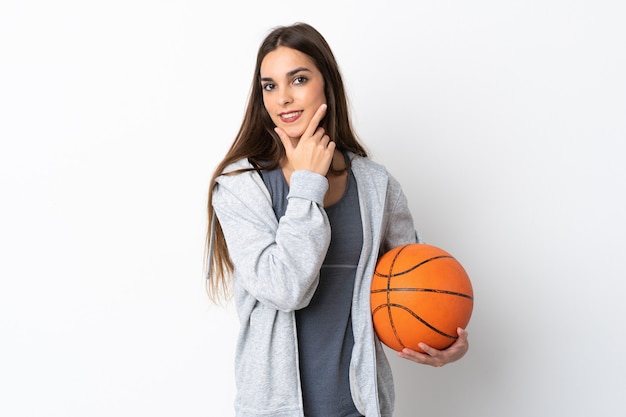 Giovane donna che gioca a basket isolato su sfondo bianco felice e sorridente