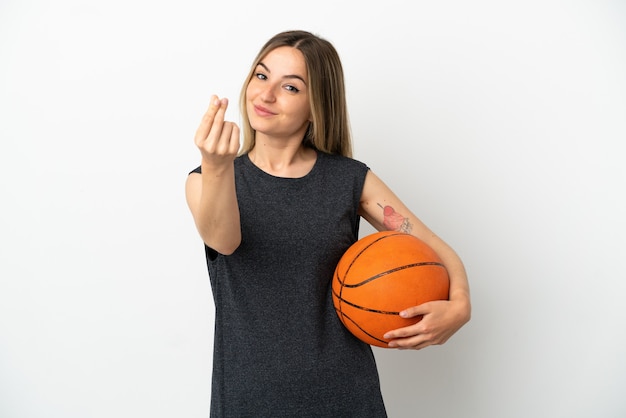 Giovane donna che gioca a basket sopra il muro bianco isolato che fa soldi gesture