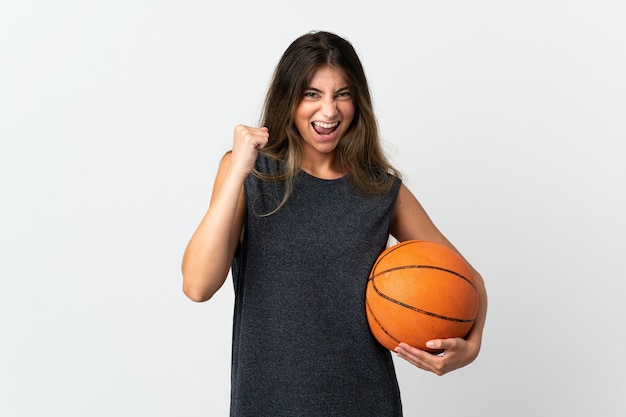 Giovane donna che gioca a basket su bianco che celebra una vittoria nella posizione del vincitore