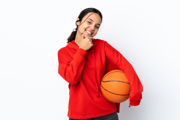 Giovane donna che gioca a basket su bianco isolato felice e sorridente