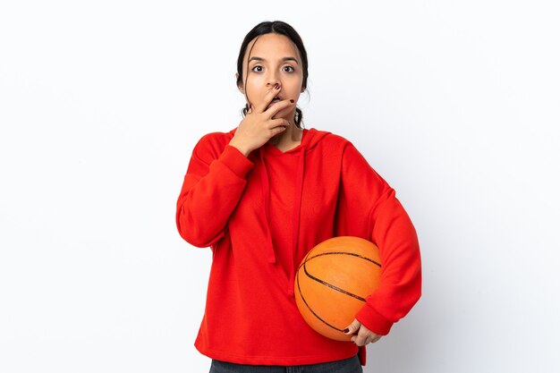 Giovane donna che gioca a basket su sfondo bianco isolato sorpreso e scioccato mentre guarda a destra