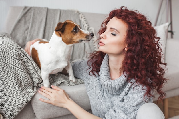 Giovane donna che gioca con il suo animale domestico. Femmina e il suo cane al coperto. Un proprietario e il suo animale domestico a casa si divertono. Jack training donna russel terrier per eseguire comandi.