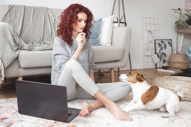 Giovane donna che gioca con il suo animale domestico. Femmina e il suo cane al coperto. Un proprietario e il suo animale domestico a casa si divertono. Jack training donna russel terrier per eseguire comandi.