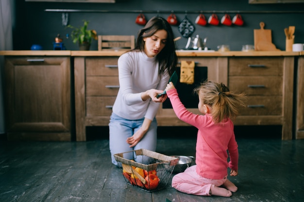 giovane donna che gioca con la sua piccola figlia in cucina.