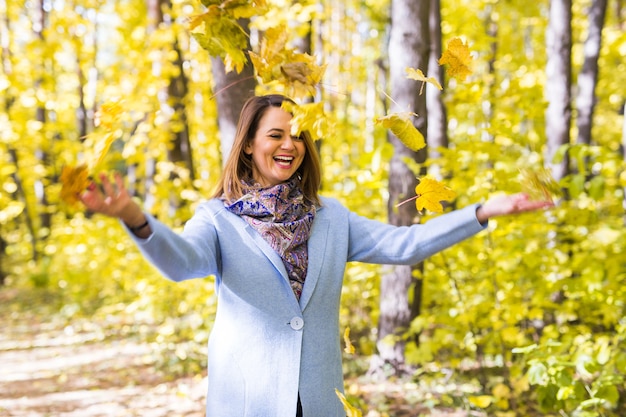 giovane donna che gioca con le foglie di autunno nel parco