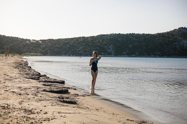 Giovane donna che gioca in mare in estate donna che si gode in acqua di mareGiovane donna allegra che si diverte sulla spiaggia È rilassata nell'acqua di mare e si diverte in vacanza