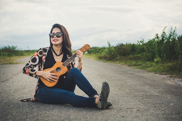 Giovane donna che gioca su Ukulele marrone nel parco.