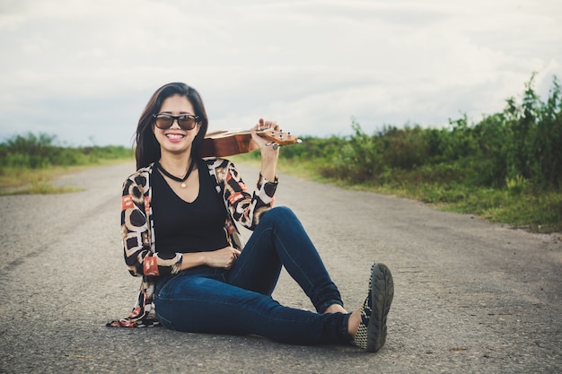 Giovane donna che gioca su Ukulele marrone nel parco.