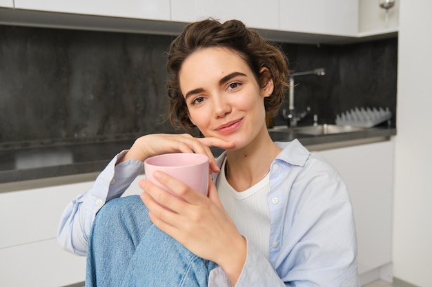 Giovane donna che gode del caffè aromatico fresco nella cucina moderna