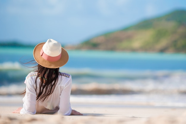 Giovane donna che gode del sole che prende il sole dall'oceano turchese perfetto