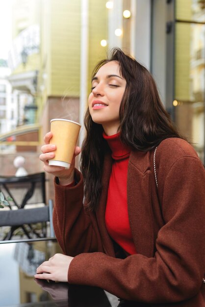 Giovane donna che gode dell'aroma del caffè per strada