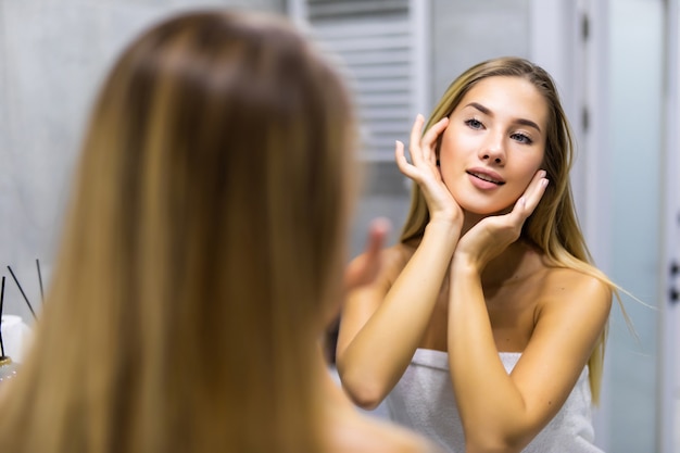 Giovane donna che guarda il riflesso nello specchio dopo la doccia