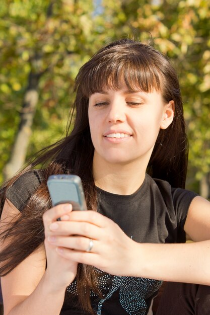 Giovane donna che guarda il suo telefono cellulare e mandare SMS.