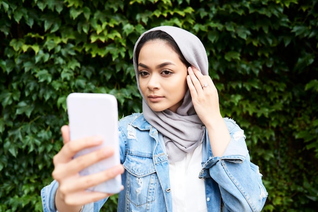 Giovane donna che guarda lo schermo del suo telefono indossando l'hijab