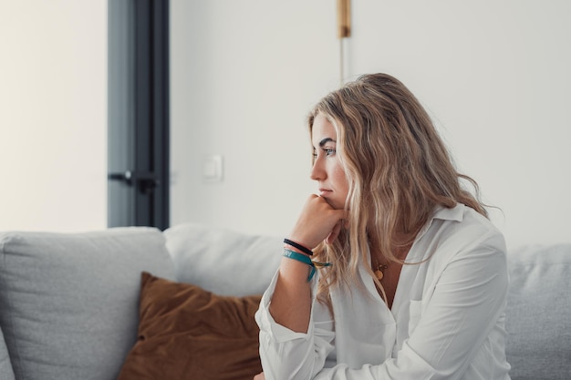 Giovane donna che guarda lontano mentre è seduta a casa