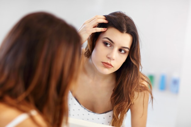 giovane donna che guarda nello specchio del bagno