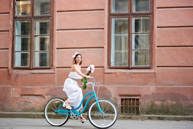 Giovane donna che guida bicicletta blu della città all'aperto