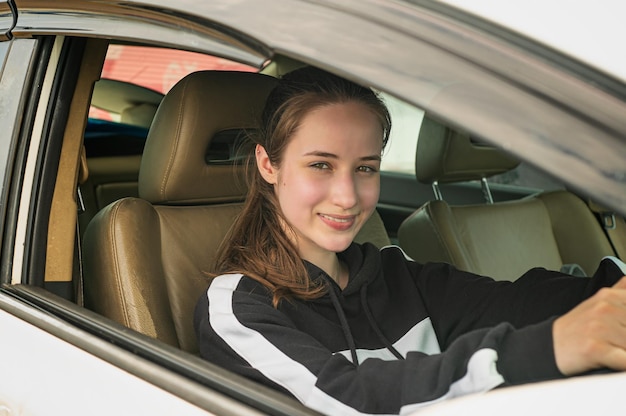 Giovane donna che guida l'auto in una giornata di sole