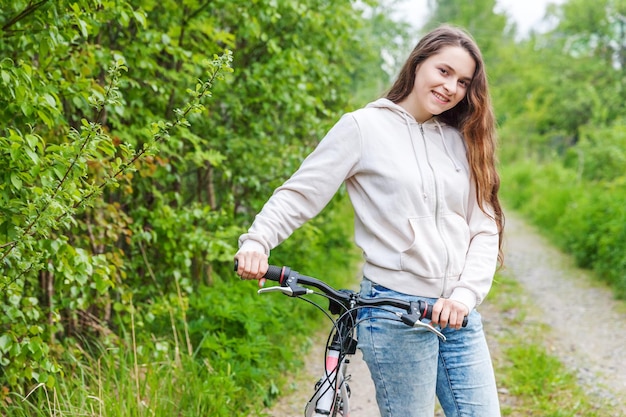 Giovane donna che guida la bicicletta nel parco cittadino estivo all'aperto Persone attive Hipster ragazza relax e bici da ciclista