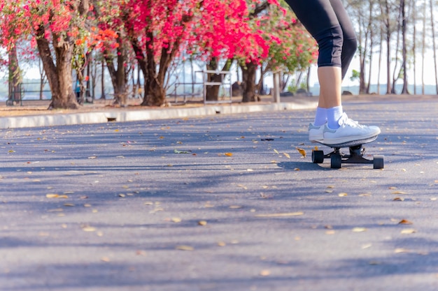 Giovane donna che guida lo skateboard della vecchia scuola lungo la strada