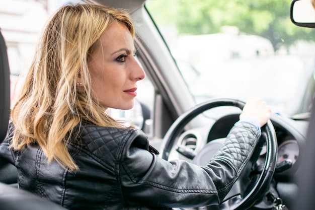 Giovane donna che guida un&#39;auto