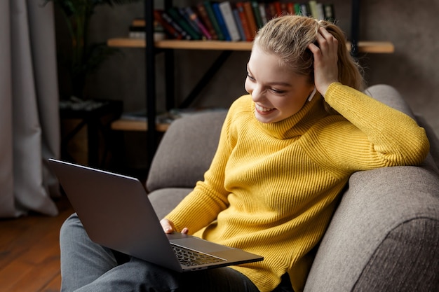 Giovane donna che ha videochiamata sul computer portatile a casa