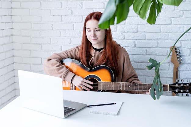 Giovane donna che impara a suonare la chitarra a casa