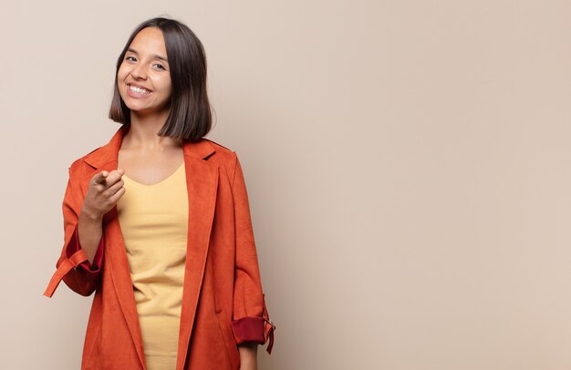 Giovane donna che indica con un sorriso soddisfatto, fiducioso, amichevole, scegliendo te