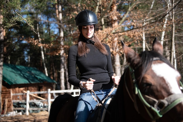 Giovane donna che indossa casco e cavallo