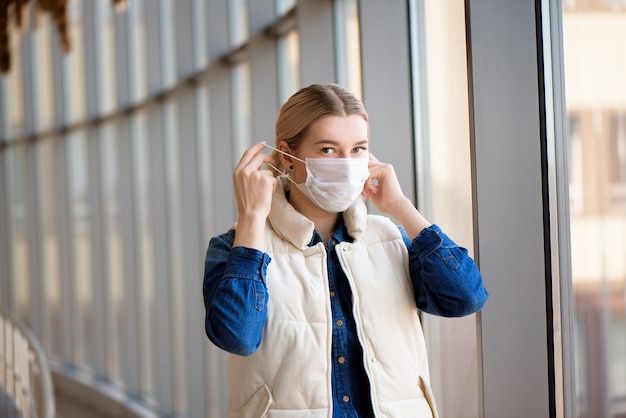 Giovane donna che indossa la maschera medica in una sala d'attesa dell'aeroporto