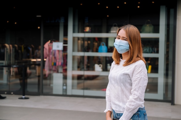 Giovane donna che indossa la maschera per il viso in strada