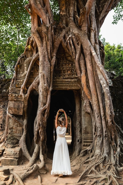 Giovane donna che indossa un abito bianco nelle antiche rovine Khmer di Angkor Wat