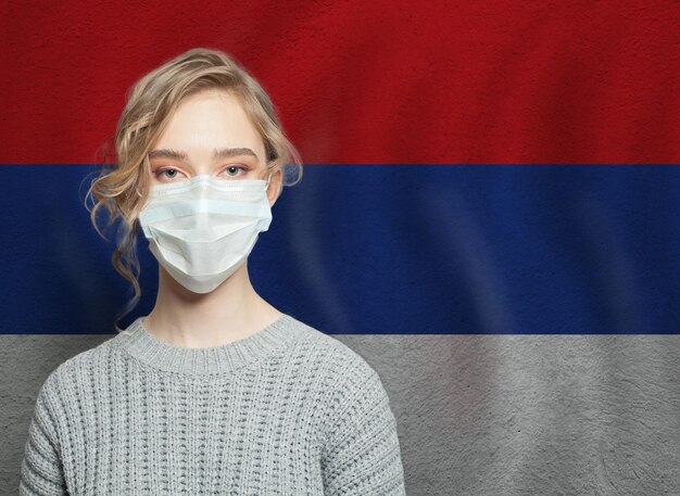 Giovane donna che indossa una maschera con la bandiera della Serbia Concept di protezione contro l'epidemia di influenza e il virus